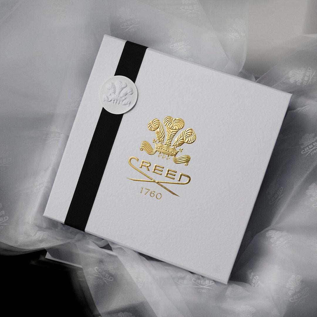 Gift box placed on top of white tissue paper embossed with Creed logo