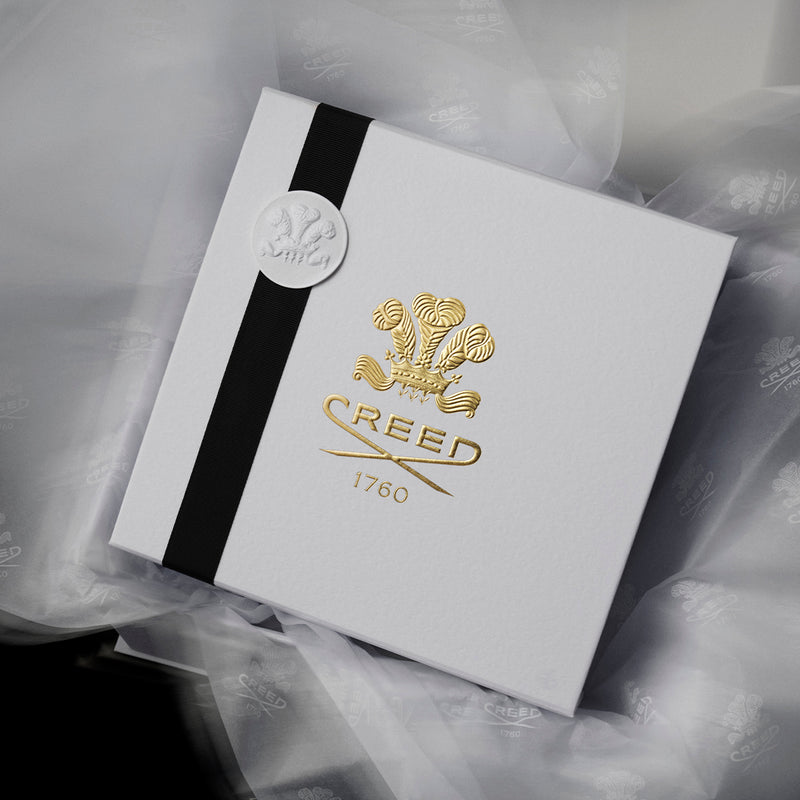 Gift box placed on top of white tissue paper embossed with Creed logo