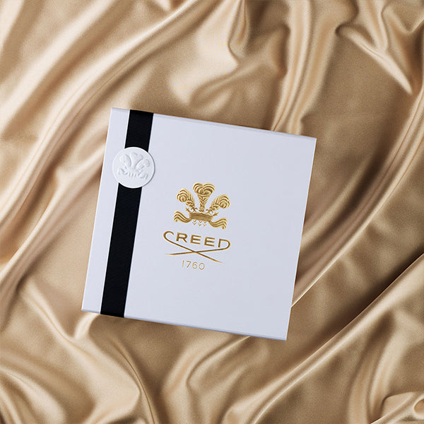White gift box with black ribbon placed on a gold silk blanket